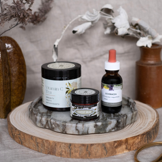 Three natural health products on a marble tray with a wooden surface and decorative plants in the background.