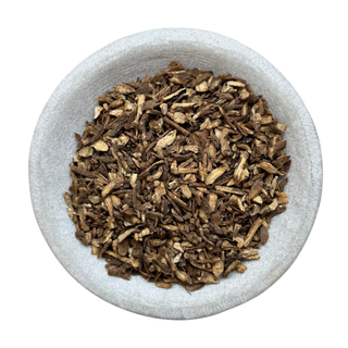 Dry herbs dong quai in a white bowl on a white background