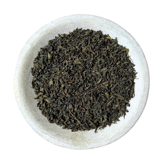 Green tea leaves in a white bowl on a white background