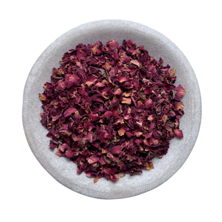 Dried red rose petals in a white bowl on a white background