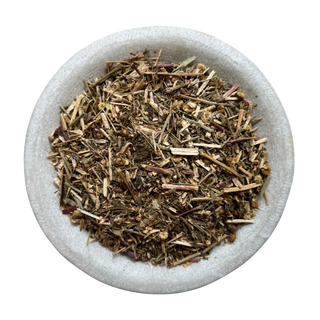 Dried feverfew in a stone bowl on a white background