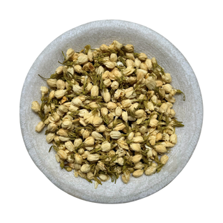Dried jasmine buds in a gray bowl on a white background