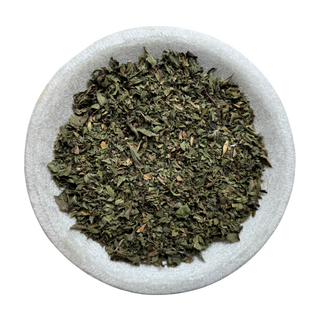 Dried peppermint in a white bowl on a white background